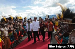 Presiden Joko Widodo (tengah) dan Ibu Negara Iriana (tengah ke-2 dari kanan) tiba di Jayapura, Papua, disambut oleh Gubernur Papua Lukas Enembe (kiri) dan istrinya Yewuce (kanan). (Foto: AFP)
