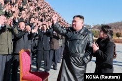 Pemimpin Korea Utara Kim Jong Un dan putrinya menghadiri sesi foto dengan para ilmuwan, insinyur, pejabat militer, dan lainnya yang terlibat dalam uji coba rudal balistik antarbenua (ICBM) baru Hwasong-17 negara itu.(Foto: KCNA via Reuters)