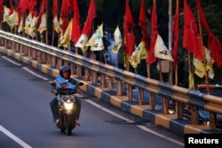 Seorang pria mengendarai sepeda motor melewati jembatan layang yang dihiasi bendera-bendera partai politik menjelang pemilu, Jakarta, 6 April 2019. (Foto: Reuters)