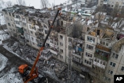 Petugas penyelamat membersihkan puing-puing bangunan tempat tinggal yang hancur akibat serangan roket Rusia di Pokrovsk, Ukraina, Rabu, 15 Februari 2023. (Foto: AP)
