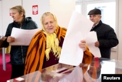 Seorang perempuan memberikan suara saat pemilihan parlemen Polandia di tempat pemungutan suara di desa Gluchow, Polandia, 15 Oktober 2023. (REUTERS/Lukasz Glowala)