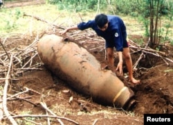 Seorang ahli penjinak bom Vietnam memeriksa bom era Perang Vietnam buatan AS yang ditemukan di desa An Nha di provinsi tengah Quang Tri, Vietnam, 2 Agustus 2001.
