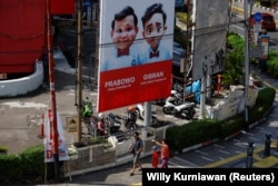 Masyarakat berjalan melewati baliho Menteri Pertahanan dan calon Presiden Prabowo Subianto dan pasangannya Gibran Rakabuming Raka di Jakarta, 12 Januari 2024. (Foto: REUTERS/Willy Kurniawan)